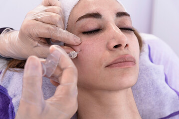 Obraz na płótnie Canvas Cosmetologist performs rejuvenating anti-wrinkle filler injections with hyaluronic acid filler in a woman's face Female aesthetic cosmetology in a beauty salon.