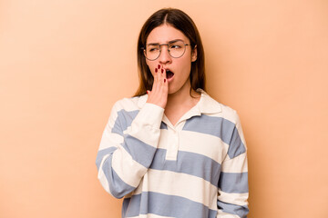 Young hispanic woman isolated on beige background yawning showing a tired gesture covering mouth with hand.
