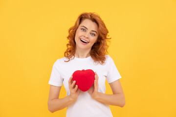 glad redhead woman hold love heart on yellow background, sweetheart