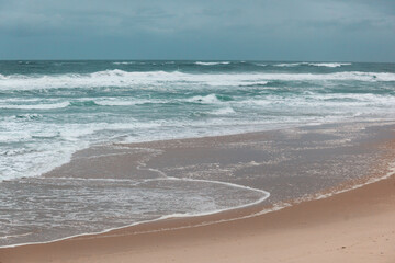 Atlantic coast, foamy waves and sandy beach. Atlantic ocean, Portugal