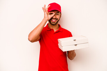 Young hispanic delivery man holding pizzas isolated on white background excited keeping ok gesture on eye.