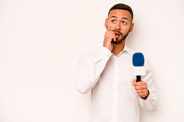 Naklejka premium Young hispanic TV presenter isolated on blue background relaxed thinking about something looking at a copy space.