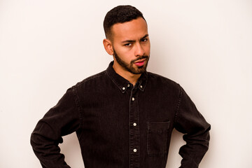 Young hispanic man isolated on white background frowning face in displeasure, keeps arms folded.