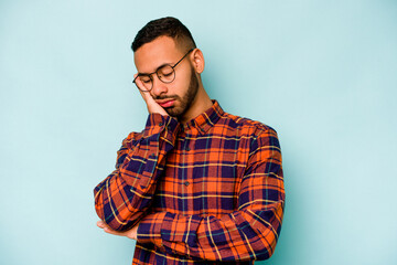Young hispanic man isolated on blue background who is bored, fatigued and need a relax day.