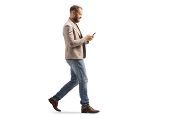 Full length profile shot of a man walking and looking at a smartphone