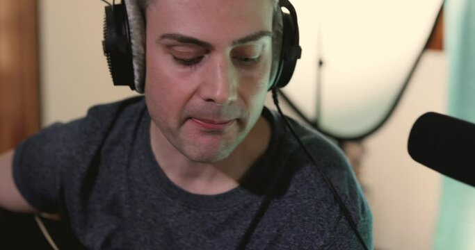Music producer singing in order to place some vocal layers for a project during a recording session at his home studio