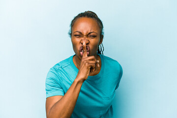 Young african american woman isolated on blue background keeping a secret or asking for silence.