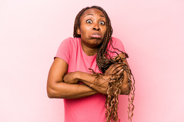Young african american woman isolated on pink background shrugs shoulders and open eyes confused.