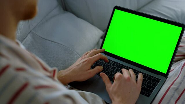 Man surfing chroma key laptop at home office. Unknown busy student writing essay