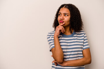 Young African American woman isolated on white background looking sideways with doubtful and skeptical expression.