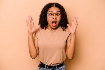 Young African American woman isolated on beige background celebrating a victory or success, he is surprised and shocked.