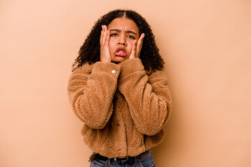 Young African American woman isolated on beige background whining and crying disconsolately.