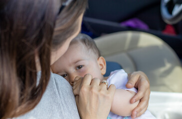 young mother breastfeeding baby boy on car seat. motherhood and lactation concept.cute adorable little boy eating breast milk.nursing infant in public.sunny .World Breastfeeding Week,august 1 august 7