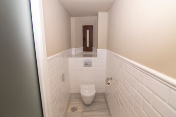 A modern and very bright toilet room. In the background a wooden window.