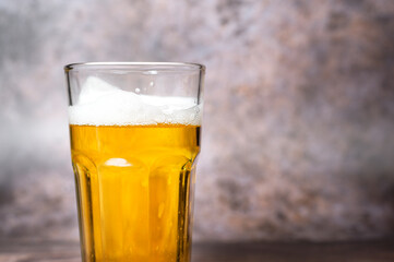 Cold craft  light Beer is pouring from bottle on wooden Table