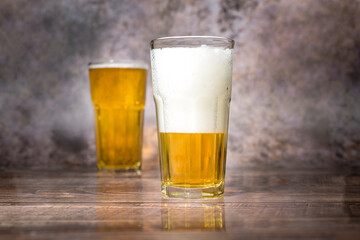 Cold craft  light Beer is pouring from bottle on wooden Table