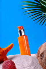 Beauty product in the sand with seashells, starfish and coconut against the blue background. Mockup...