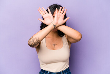 Young hispanic woman isolated on purple background keeping two arms crossed, denial concept.