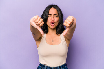 Young hispanic woman isolated on purple background showing thumb down and expressing dislike.