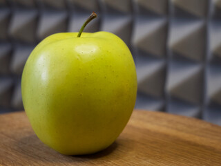 Golden Delicious is a yellow apple, one of the 15 most popular cultivars in the United States. A single apple on a wooden surface, close-up.