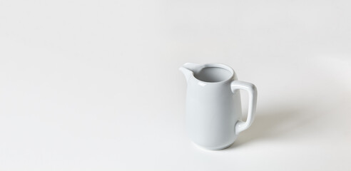 Milk jug on white background. Porcelain sauce boat, pitcher, creamer or ceramic gravy boat. Space for text, for advertising, banner, signboard, menu and printed materials