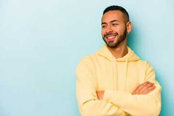 Young hispanic man isolated on blue background smiling confident with crossed arms.