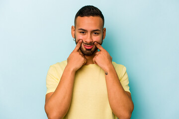 Young hispanic man isolated on blue background doubting between two options.
