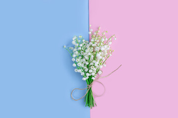 Bouquet of lilies of the valley on blue and pink background. Flat lay, top view, copy space. floral background with spring flowers. Mother's day, Valentines Day, Birthday celebration concept