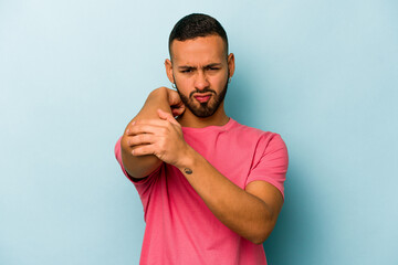 Young hispanic man isolated on blue background having a neck pain due to stress, massaging and touching it with hand.