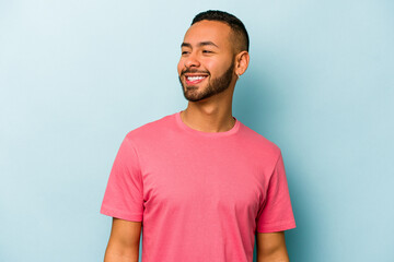 Obraz premium Young hispanic man isolated on blue background relaxed and happy laughing, neck stretched showing teeth.