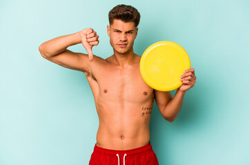 Young caucasian man playing with frisky isolated on blue background showing a dislike gesture,...