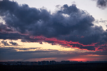 A large dark cloud with a glimmer of light from the red setting sun