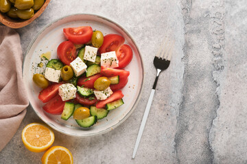Greek salad. Fresh Greek salad with fresh vegetables, tomato, cucumber, green olives and feta cheese on old grey concrete table background. Top view.