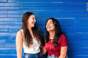 two hispanic friends female using brackets laughing together.