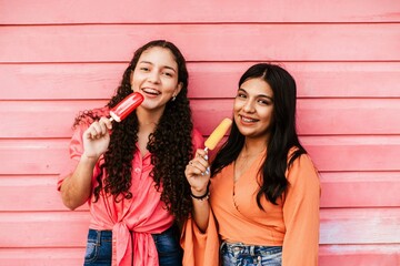 portrait of friends latin women eating a popsicle. - Powered by Adobe