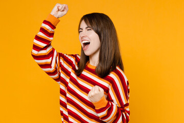 Side view young happy excited overjoyed woman 20s in red striped sweatshirt doing winner gesture...