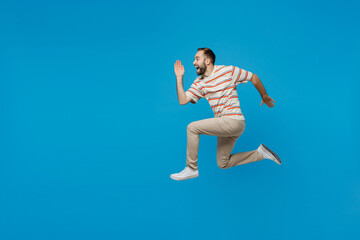Fototapeta na wymiar Full body side profile view young excited happy fun caucasian man 20s wearing orange striped t-shirt run fast hurry upisolated on plain blue color background studio portrait. People lifestyle concept.