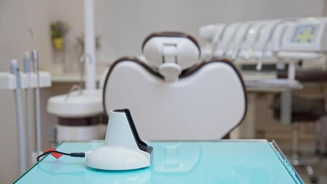 A dentist's assistant in black gloves shows how to work properly with a polymerization lamp in a medical office. A lesson for dentists and their assistants.