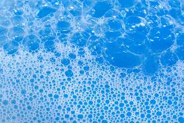 Fototapeta na wymiar Soap foam. Background of dusty foam with bubbles of blue color for an inscription. Soap sud with copy-space