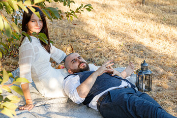beautiful girl in a white dress and a guy lie in a clearing, a picnic