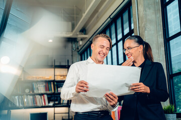 Attractive Caucasian businessman and businesswoman, Engineer,Architect colleagues coworker are working to discuss on blueprint, project strategy plan, find solution, analyze problems in modern office