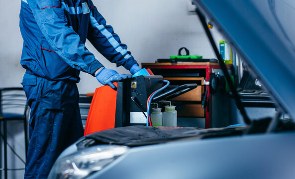 Hands of auto mechanic include the installation of refilling the air conditioner in car service