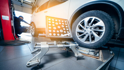 Auto mechanic installing sensor during suspension adjustment and automobile wheel alignment work at...