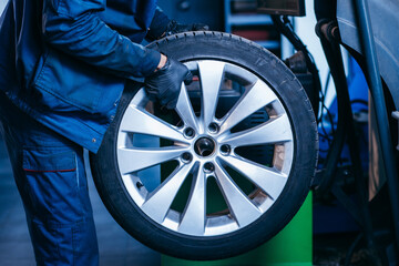 Auto mechanic uses tire balancing machine and turning tire