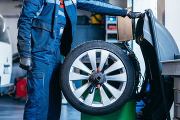 Auto mechanic uses tire balancing machine and turning tire