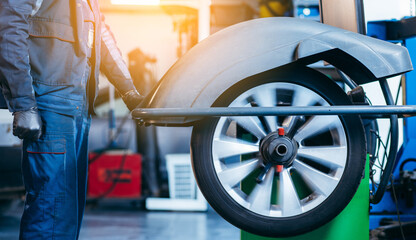 Auto mechanic uses tire balancing machine and turning tire