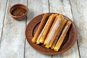 Fototapeta na wymiar traditional Spanish pastries - Churros and chocolate sauce on a wooden background