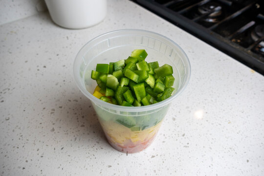 View Of Coloful Diced Bell Peppers In A Plastic Container On A Kitchen Counter, Prepped For Cooking