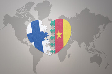 puzzle heart with the national flag of cameroon and finland on a world map background. Concept.