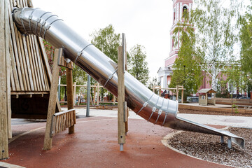 Round metal tube slide, children's playground outside, slide skiing, modern park for family holidays in the city.